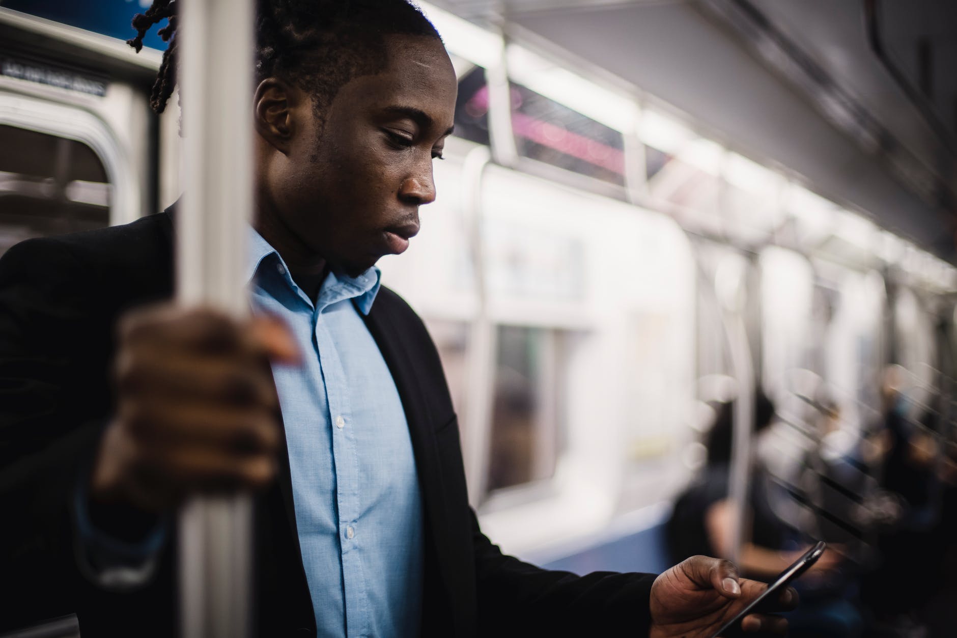 african american office worker using smartphone while commuting by train