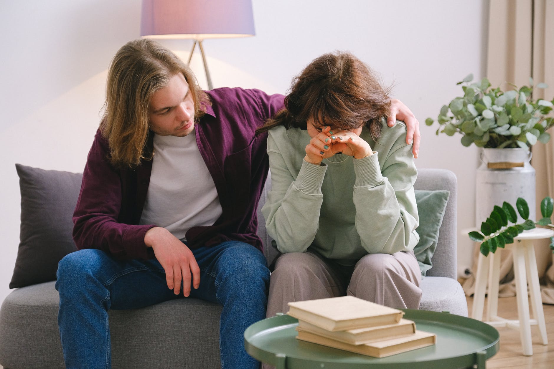 man soothing crying sad woman on sofa