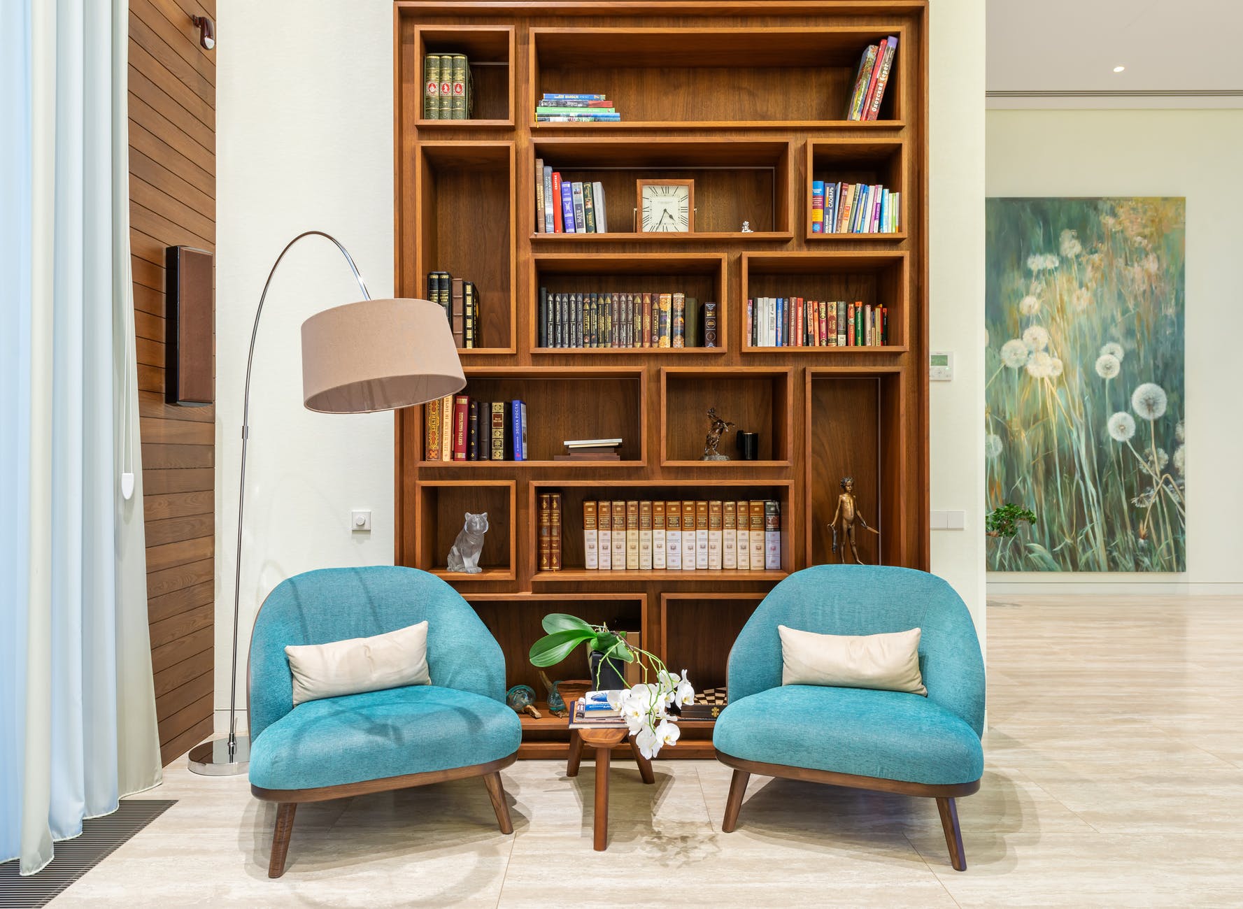 living room with cozy chairs near lamp and wooden bookcase