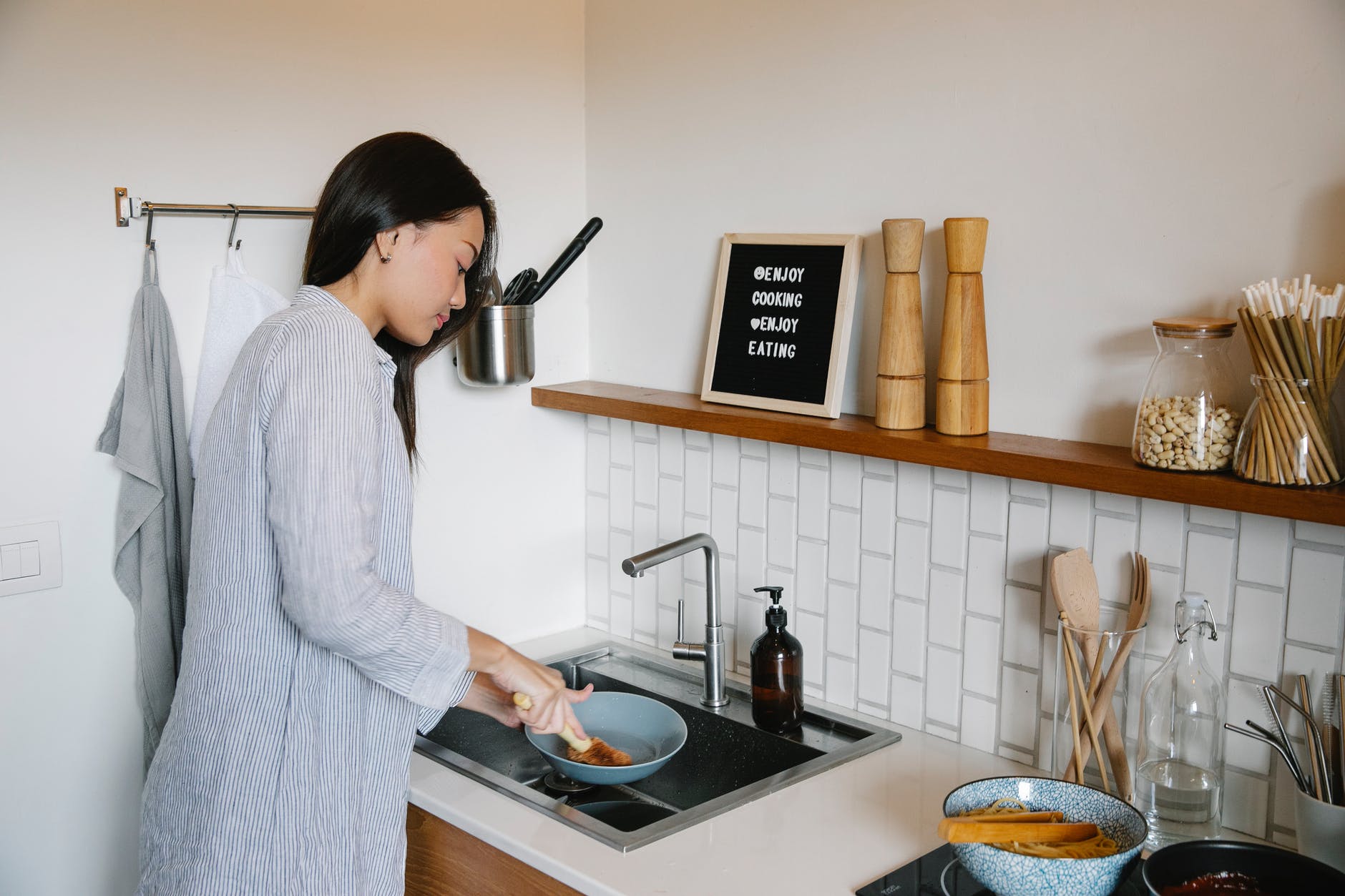 focused asian woman washing dishes