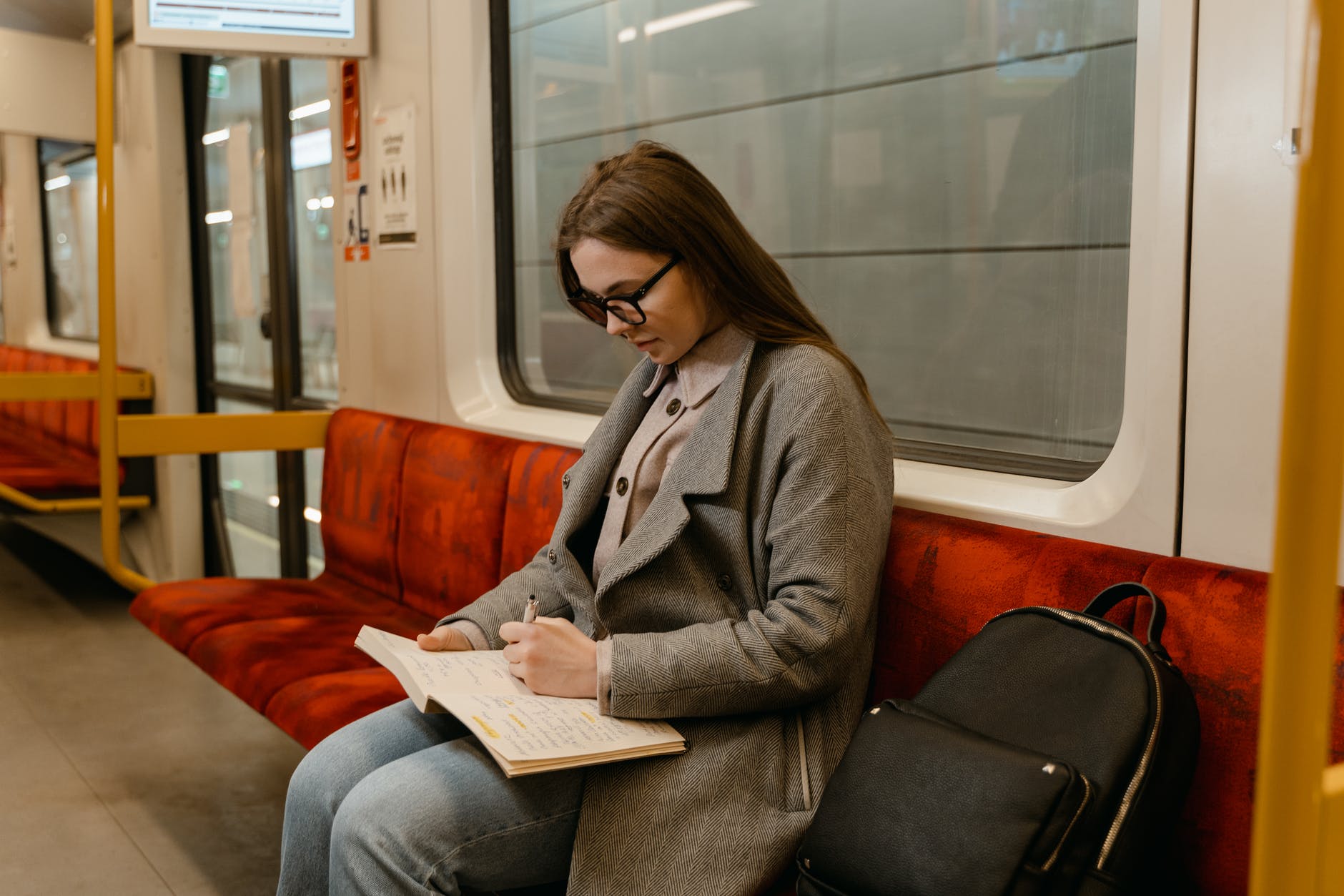 a woman writing on a book sitting in a train